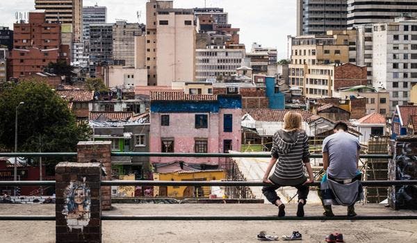 to personer som sitter med ryggen til kamera foran en favela 